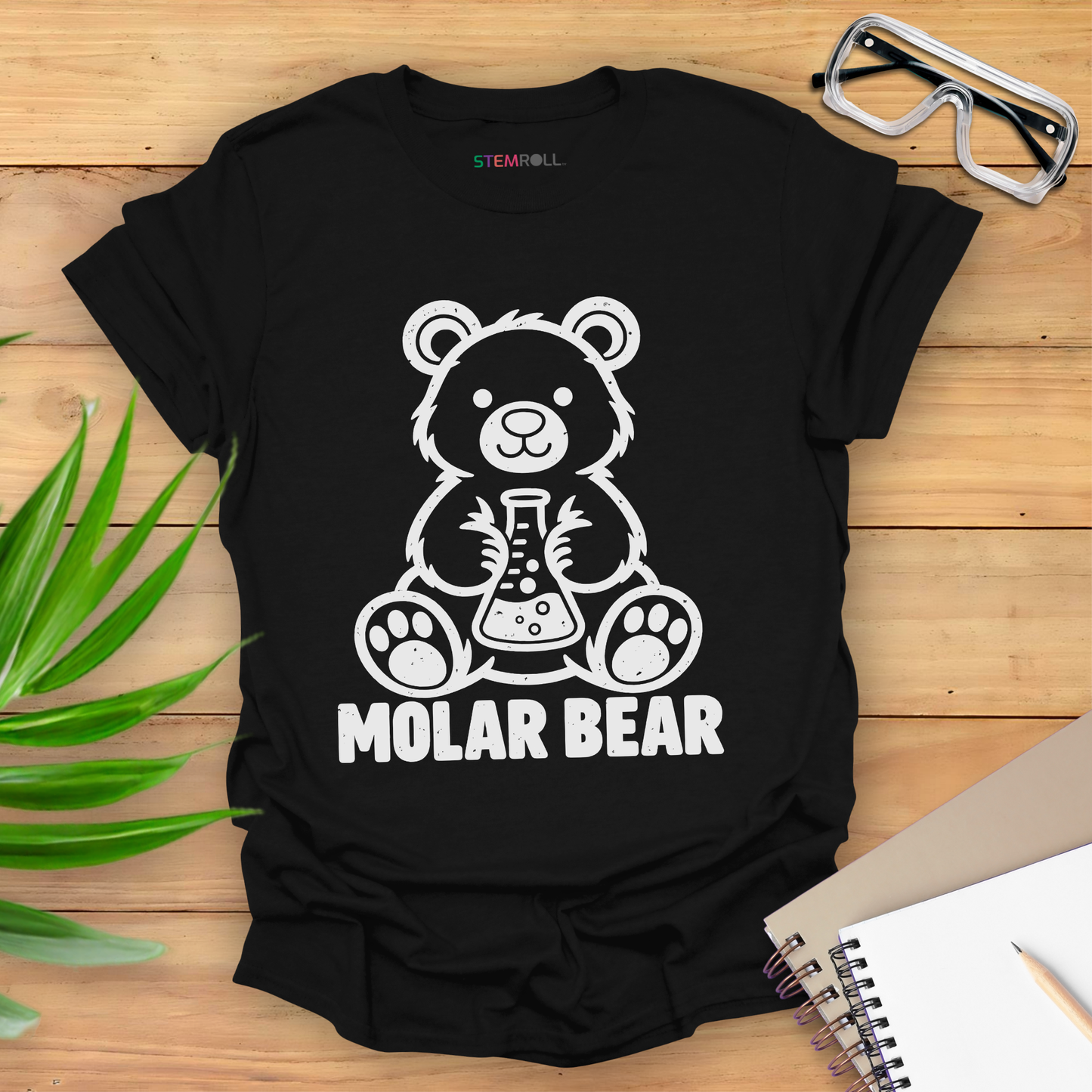 Molar Bear chemistry t-shirt in black, flat lay with safety goggles and notebook